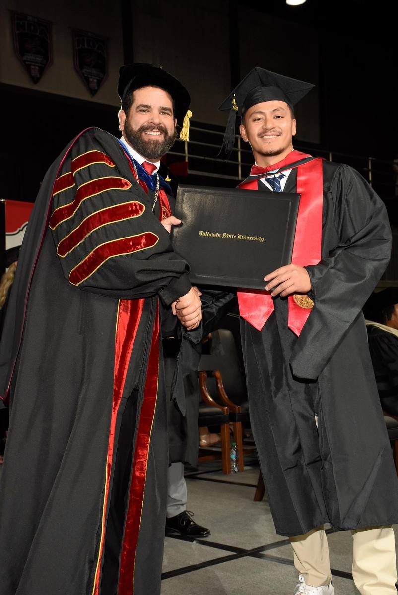 Kelvin in cap and gown receiving his Valdosta State University diploma.
