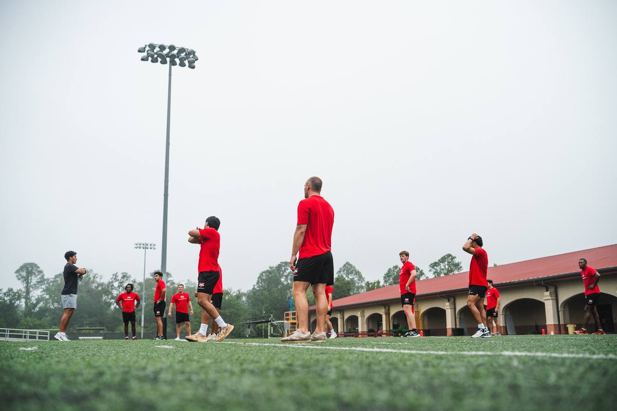 A baseball team spread across a field on a foggy morning during a training session.