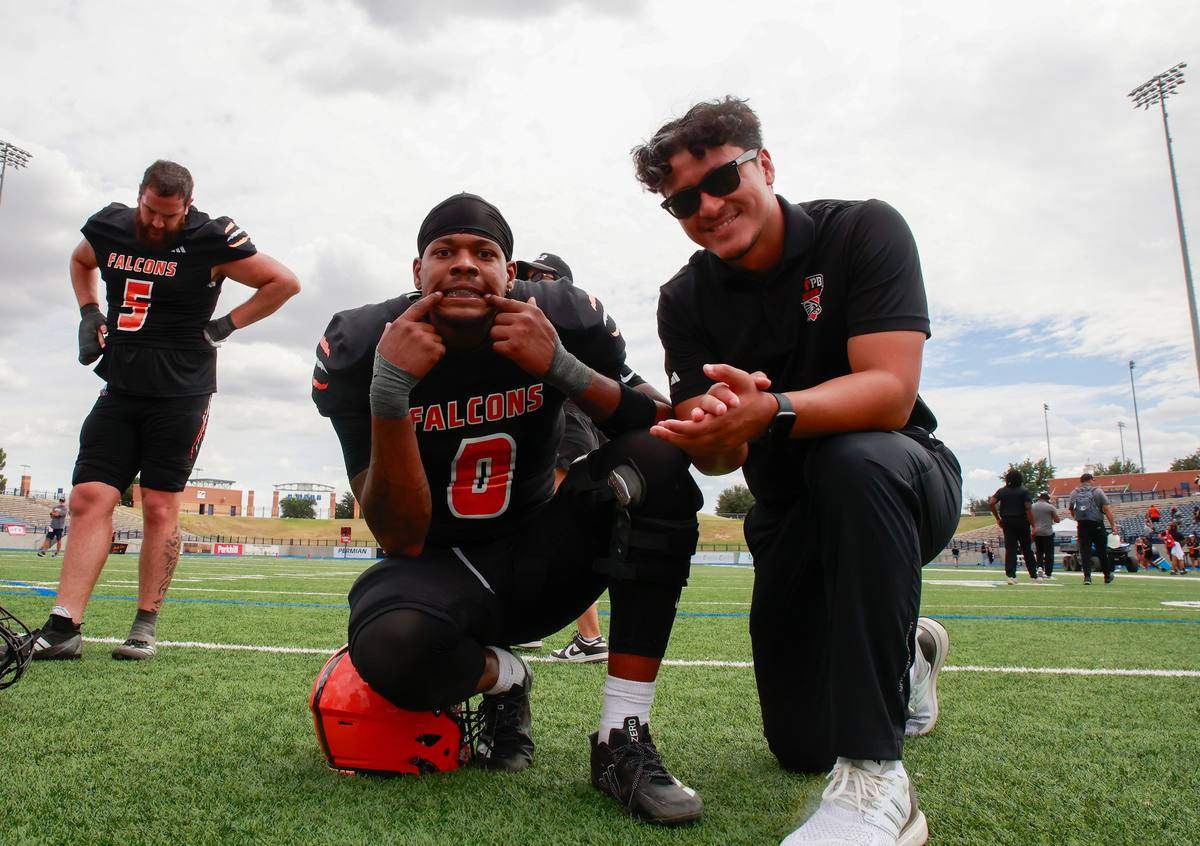 Kelvin kneeling on the field with a UTPB Falcons player after a game.