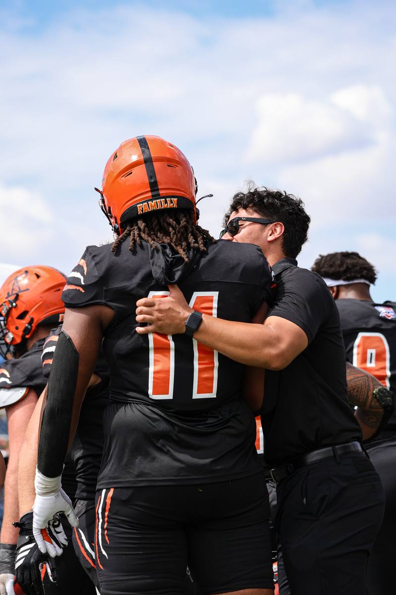 Kelvin embracing a UTPB football player on the sideline.